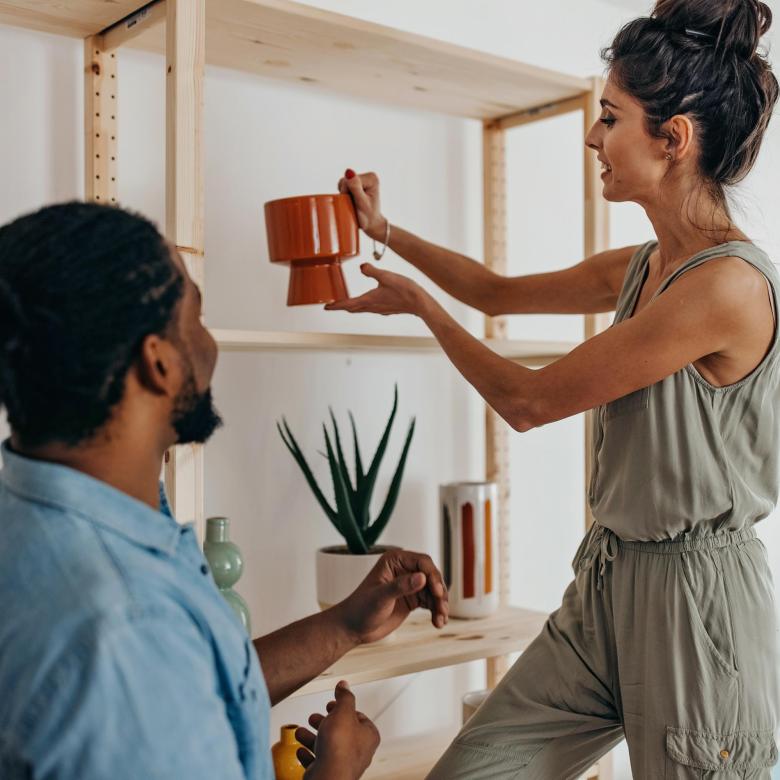 A happy young couple placing a vase on a shelf and deciding how to decorate their new home
